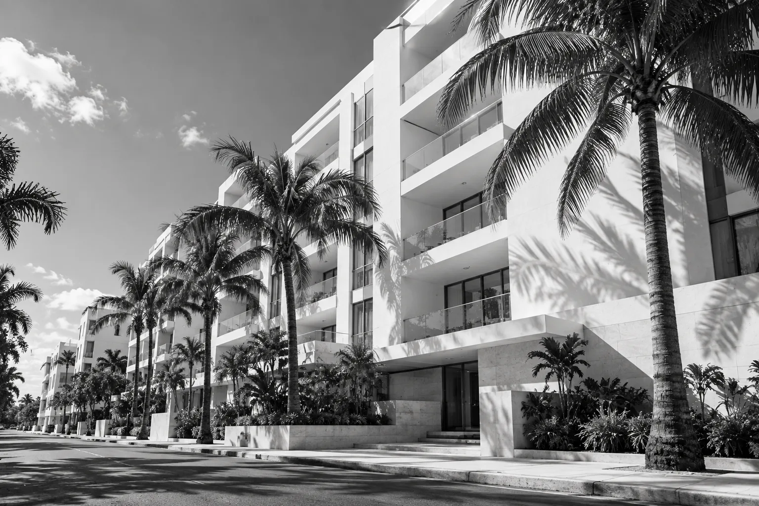 Fachada de un edificio residencial blanco con balcones, entre palmeras